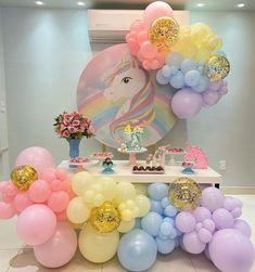 a table topped with balloons and unicorns next to a wall mounted painting on the wall