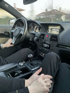 a woman is sitting in the driver's seat of a car with her hands on the steering wheel