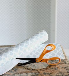 two pairs of scissors sitting on top of a counter next to a roll of paper