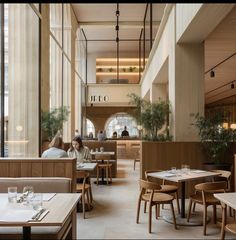 people sitting at tables in a restaurant with large windows on the wall and wooden booths