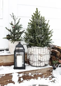 a lantern and christmas tree in front of a white house with snow on the ground