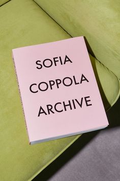 a pink book sitting on top of a green couch next to a white pillow with the words sofia coppola archive written on it