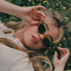 a woman laying in the grass wearing sunglasses