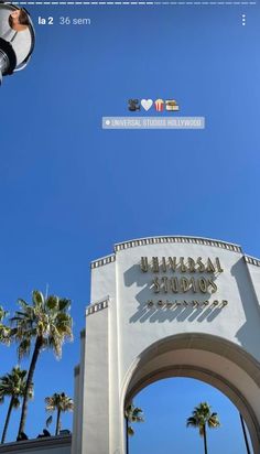 the entrance to universal studios hollywood with palm trees in the foreground and an overhead sign above it