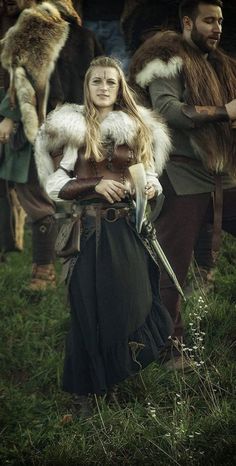 a group of people dressed in costume standing on top of a grass covered field next to each other