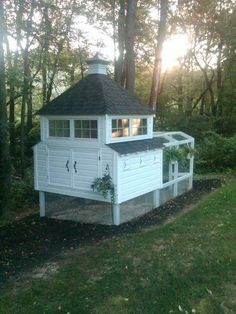 a white house with a black roof in the woods