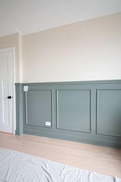 an empty room with wood flooring and walls painted in pale blue, white and beige