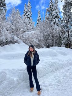 a woman is standing in the snow near some trees