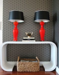 two red lamps sitting on top of a white table next to a black and white wall