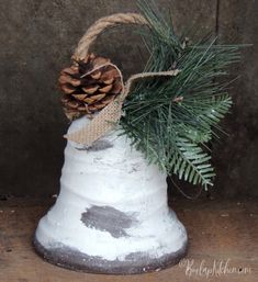 a small white bell with a pine cone on top and burlock around it