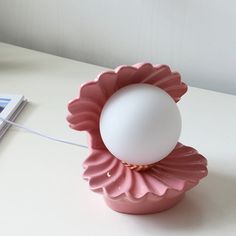 an egg sitting on top of a pink flower shaped container next to a remote control