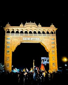 people are standing in front of an arch at night