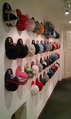 a wall filled with lots of hats hanging on it's side walk next to a doorway