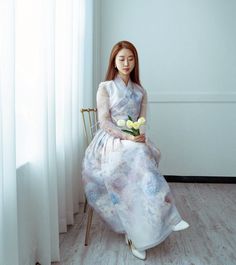 a woman sitting on a chair with flowers in her hand