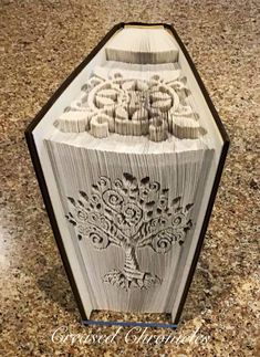 an intricately carved book sculpture on top of a granite countertop in the shape of a tree