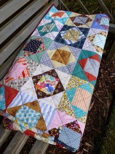 a patchwork quilt sitting on top of a wooden bench