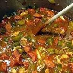 a pot filled with stew and vegetables being stirred by a wooden spoon