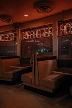 the interior of a restaurant with neon signs on the windows and leather booths in front