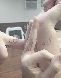 two people with matching tattoos on their fingers, one has an elephant and the other has a giraffe