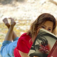 a woman laying on the ground reading a book