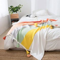 an unmade bed with blankets and pillows on top of it in a white room