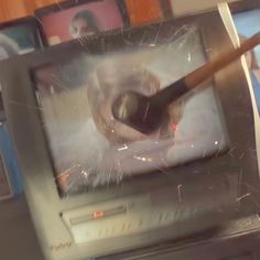 an old television with a cat on it's screen and a pencil sticking out of the screen