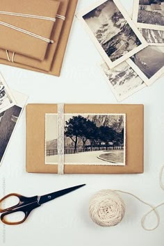 an open book with pictures and twine on it next to yarn, scissors and photos