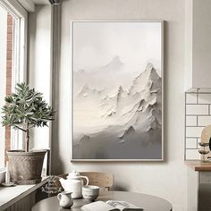 a painting hanging on the wall above a table in front of a potted plant