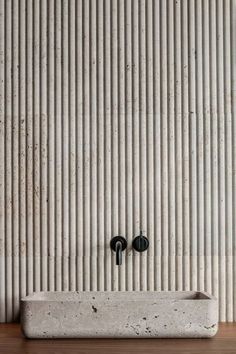 two black knobs on the side of a white wall with vertical lines behind them