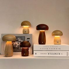 three mushroom shaped lights are on top of a shelf next to a book and photo