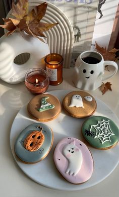 decorated cookies on a white plate with candles and decorations in the shape of ghostes