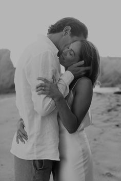 a man and woman kissing on the beach