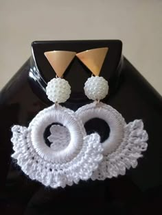 a pair of white and gold earrings sitting on top of a black table