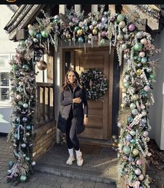 a woman standing in front of a doorway with christmas decorations on the outside and inside