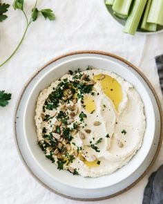 a white bowl filled with hummus and green vegetables