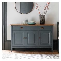 a blue buffet table with two vases and a mirror on the wall above it