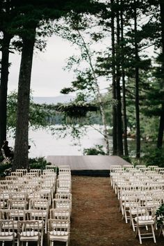 rows of chairs set up for an outdoor wedding ceremony in the woods near a lake