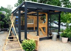 a small wooden structure in the middle of a yard with potted plants around it