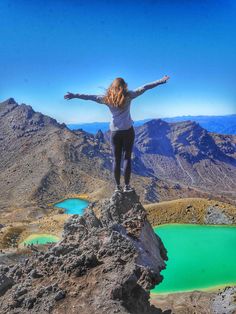 a woman standing on top of a mountain with her arms wide open and hands in the air