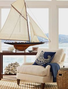 a living room with a chair and a sailboat on the table in front of it