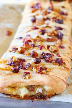 a long piece of bread with cranberry toppings sitting on a baking sheet