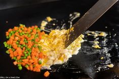 a person is cutting up some food on a black plate with a knife in it