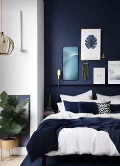 a bedroom with dark blue walls, white bedding and art on the wall above it