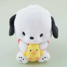 a white stuffed animal with black ears holding a yellow duck