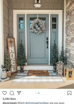 a blue front door with two christmas trees on the side and a welcome mat in front