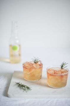 two glasses filled with drinks sitting on top of a white tray next to a bottle