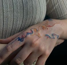 a woman's hand with colorful tattoos on it