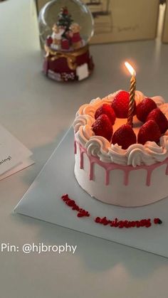 a birthday cake with white frosting and strawberries on top is lit by a single candle