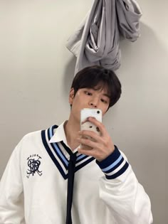 a young man taking a selfie in front of a mirror with his cell phone