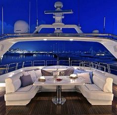 the inside of a boat with couches, tables and chairs on it at night